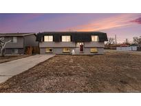 Two-story home with red door, neutral siding, and a well-maintained, xeriscaped front yard at dusk at 206 Cedar St, Hudson, CO 80642