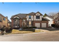 Charming two-story Tudor-style home with a brick facade, attached two-car garage, and manicured front lawn at 6251 S Iola Ct, Englewood, CO 80111