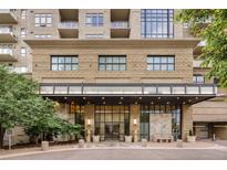 Elegant building entrance featuring stone facade, modern glass doors, and manicured landscaping at 5455 Landmark Pl # 1009, Greenwood Village, CO 80111