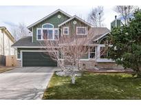 Charming two-story home with green siding, stone accents, a two-car garage, and a well-maintained front lawn at 19634 E Clear Creek Trl, Parker, CO 80134