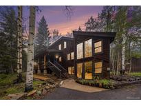 Modern exterior featuring wood paneling, large windows, and a picturesque natural setting with stunning sunset colors at 10419 Christopher Dr, Conifer, CO 80433