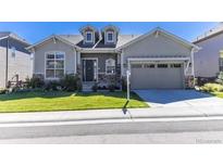 Charming single-story home featuring a well-maintained lawn, a two-car garage, and beautiful stone accents at 14160 Ivanhoe St, Thornton, CO 80602