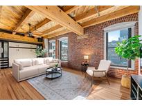 Bright living room with exposed brick wall, wood beams, and stylish contemporary furniture at 1745 Wazee St # 3C, Denver, CO 80202