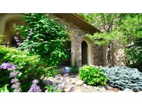 Charming home entrance with stone facade, lush greenery, and vibrant flowers. Great curb appeal! at 10328 Bluffmont Dr, Lone Tree, CO 80124