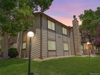 Exterior view of home with brown siding, a stone chimney, and manicured lawn at 1870 S Pitkin Cir # B, Aurora, CO 80017