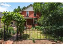 Charming brick home with a landscaped front yard and black iron fence, providing a welcoming curb appeal at 131 Fox St, Denver, CO 80223