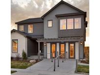Beautiful two story home featuring a mix of siding and stone, covered entryway, and manicured lawn at 9973 Worchester St, Commerce City, CO 80022