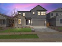 Two-story gray home featuring a two-car garage, manicured lawn, and inviting front entrance at 9973 Worchester St, Commerce City, CO 80022