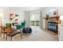 Bright living room featuring a stone fireplace, an emerald green velvet couch, and balcony access at 3452 S Eagle St # 101, Aurora, CO 80014
