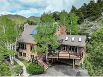 Charming multi-level home with stone accents, a deck, and nestled amongst lush trees at 34127 Cactus Dr, Evergreen, CO 80439