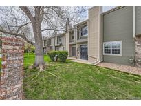 View of the condo with a well-maintained lawn with a large tree for shade and brick wall at 3415 S Ammons St # 24-2, Lakewood, CO 80227