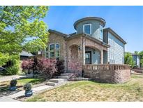 Charming two-story home featuring stone accents, arched entryway, and a well-maintained front yard with mature trees at 9530 E 113Th Ave, Commerce City, CO 80640