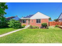 Charming brick home with a well-maintained lawn, tidy landscaping, and solar panels on a sunny day at 755 S Clay St, Denver, CO 80219