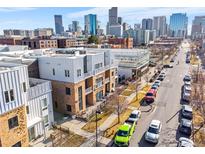 Modern townhomes with brick and metal exteriors in a vibrant cityscape with tree lined street and sidewalks at 2530 Lawrence St # Ra101, Denver, CO 80205