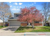 Charming two-story home with a well-manicured lawn and a beautiful flowering tree in the front yard at 4860 S Field Way, Littleton, CO 80123