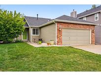 Charming exterior with a brick-accented two-car garage and a well-manicured lawn at 13313 Cherry Cir, Thornton, CO 80241