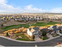 Expansive aerial view of a community with golf course and mountain backdrop on a partly cloudy day at 2631 Red Hawk Ridge Dr, Castle Rock, CO 80109