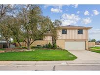 Inviting two-story home featuring a well-manicured lawn and mature trees, showcasing great curb appeal at 7264 S Platte Canyon Dr, Littleton, CO 80128