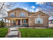 Inviting two-story home featuring a covered porch, stone accents, and a well-manicured lawn at 3422 Vestal Loop, Broomfield, CO 80023