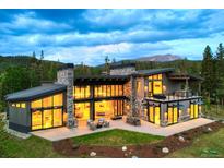 Stunning mountain home featuring expansive windows, stone accents, and outdoor living spaces against a scenic backdrop at 132 N Gold Flake Ter, Breckenridge, CO 80424
