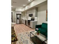 Bright living room featuring a modern kitchen and a comfortable emerald green couch at 2876 W 53Rd Ave # 305, Denver, CO 80221
