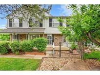 Charming townhome featuring a mix of brick and siding, complemented by lush greenery and mature trees at 9930 W Progress Pl, Littleton, CO 80123