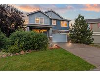 Charming two-story home with blue siding, stone accents, lush landscaping, and an attached two-car garage at 19067 W 57Th Dr, Golden, CO 80403