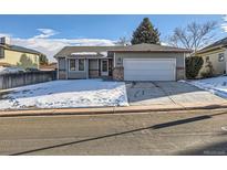 Ranch style home with attached garage and snow-covered front yard at 14942 E Evans Ave, Aurora, CO 80014