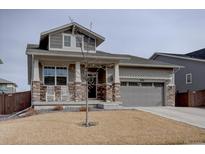 Charming two-story home with stone accents, covered porch, and manicured lawn at 2785 Black Hawk Pl, Brighton, CO 80601