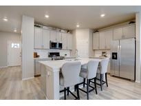 Modern kitchen features stainless steel appliances, white cabinets, and a center island with seating at 2785 Black Hawk Pl, Brighton, CO 80601