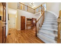 Grand foyer featuring hardwood floors, a curved staircase, and a second-floor balcony at 10375 Lions Heart, Lone Tree, CO 80124