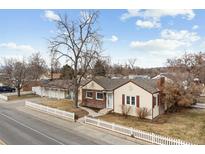 Charming single-story home with brick accents, red shutters and a well-maintained lawn and white picket fence at 8001 W 57Th Ave, Arvada, CO 80002