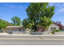 Charming home with a white picket fence and a mature tree in front of the home at 8001 W 57Th Ave, Arvada, CO 80002