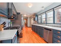 Modern kitchen featuring stainless steel appliances, quartz countertops, and updated cabinetry at 8001 W 57Th Ave, Arvada, CO 80002