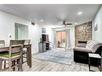 Bright living room with a stone fireplace, ceiling fan, wood-look floors and sliding glass doors to the patio at 420 Wright St # 101, Lakewood, CO 80228