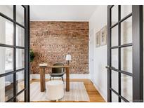 Charming home office with exposed brick wall, wood desk, and natural light streaming through glass doors at 1000 N Ogden St, Denver, CO 80218