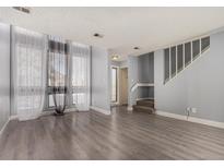 Bright living room features large windows with sheer curtains and gray wood-look flooring at 4950 Homestead Pl # 23, Thornton, CO 80229