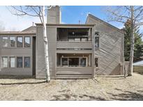Exterior view of a two-story condo featuring double balconies, a wood-paneled facade, and mature trees at 23561 Genesee Village Road # C, Golden, CO 80401