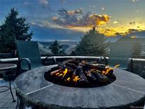 Inviting fire pit with seating under a dramatic sunset sky, perfect for outdoor gatherings at 20249 Terrace View Dr, Parker, CO 80134