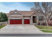 Charming home featuring stone accents, red garage doors, and a well-maintained lawn at 21270 E Eldorado Dr, Aurora, CO 80013