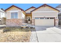 Charming home featuring a brick facade, a two-car garage and a well-maintained yard with mature landscaping at 9814 Norfolk St, Commerce City, CO 80022