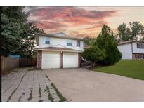 Inviting home featuring a two-car garage, mature trees, and a well-maintained lawn at 1775 S Memphis St, Aurora, CO 80017