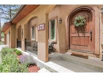 Inviting front porch features a lovely arched doorway, beautiful landscaping, and a cozy seating area at 171 Columbine St, Larkspur, CO 80118