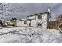 Charming two-story home with white siding, a front yard covered in snow and attached garage at 15689 E Eastman Pl, Aurora, CO 80013