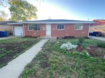 Charming one-story brick home with a walkway and flower beds at the front of the house at 106 Emerald St, Broomfield, CO 80020