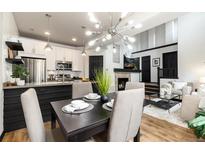 Contemporary dining room with striking chandelier, open to modern kitchen and fireplace, with hardwood flooring at 7777 E 23Rd Ave # 201, Denver, CO 80238