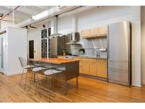 Modern kitchen with stainless steel appliances, a wood island and hardwood flooring at 2955 Inca St # 2F, Denver, CO 80202