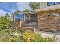 Inviting brick home entrance with a well-manicured garden and a charming, secured front door at 7232 S Costilla St, Littleton, CO 80120