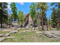 Charming home with a welcoming entrance and natural rock landscaping in a serene, wooded setting at 11421 Belle Meade Dr, Conifer, CO 80433