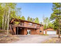 Charming two-story home featuring a spacious deck and attached garage amidst a lush forest setting at 11457 Nancys Dr, Conifer, CO 80433